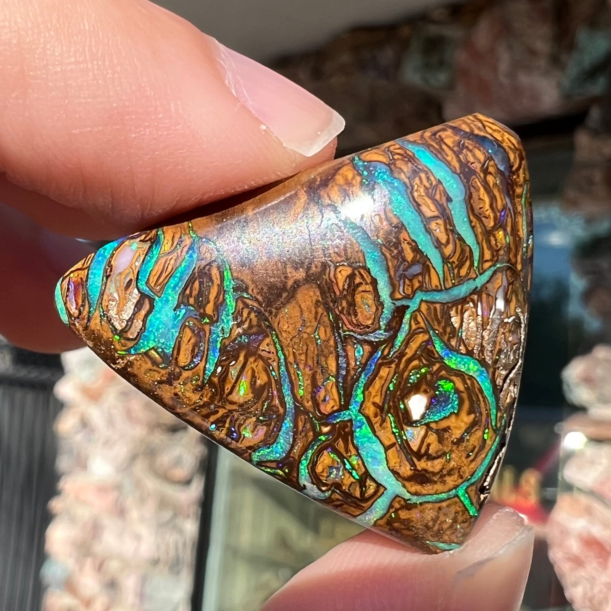 A triangle shaped Koroit boulder opal.  The stone has blue veins of opal running through it.