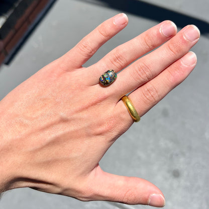 A loose, Koroit boulder opal stone.  The opal plays bright blue and green colors on a patterned matrix.