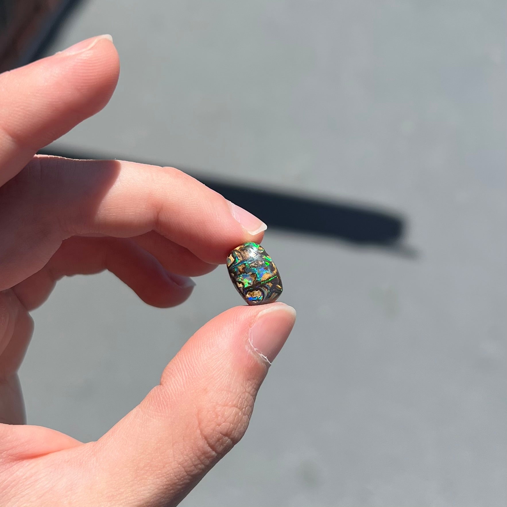 A loose, Koroit boulder opal stone.  The opal plays bright blue and green colors on a patterned matrix.