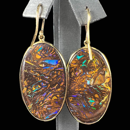 A pair of Koroit boulder opal dangle earrings set in yellow gold bezels.