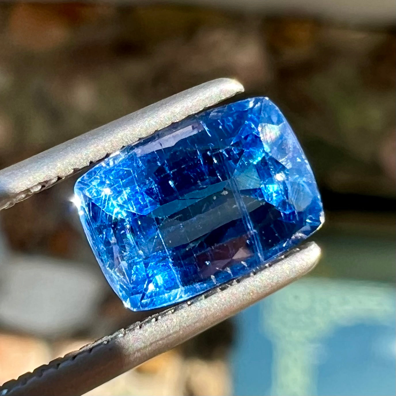 A loose, blue kyanite gemstone.  The stone is a faceted cushion cut.