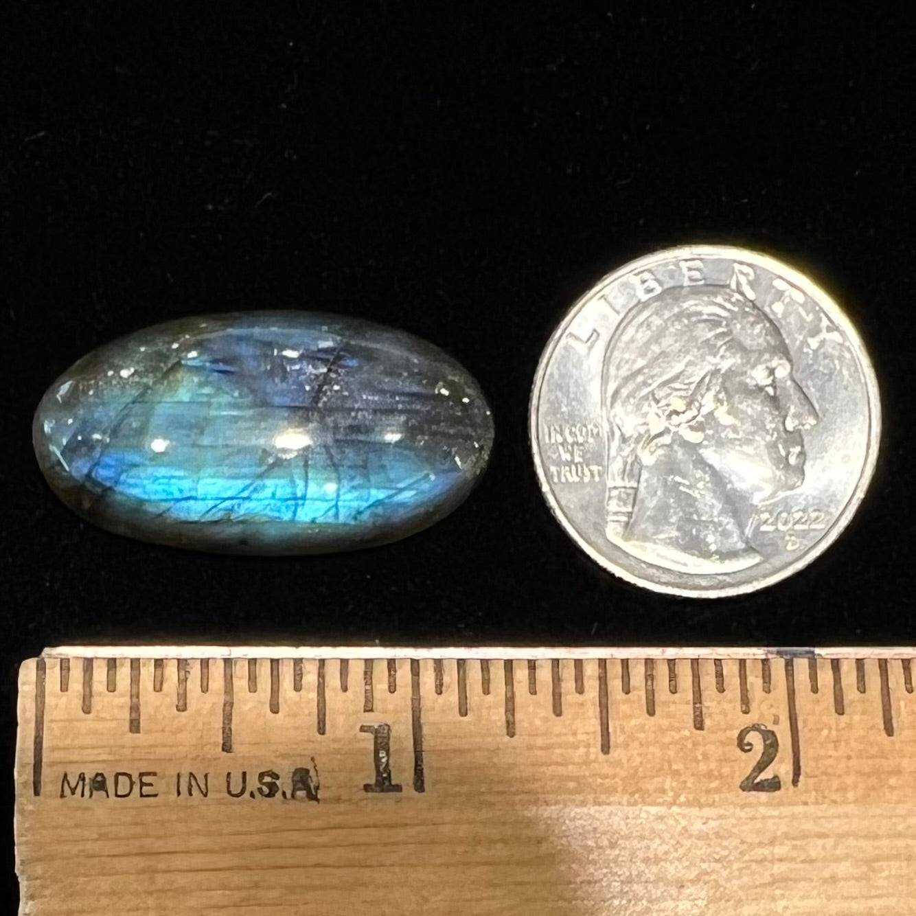 A loose, oval cabochon cut labradorite feldspar stone.  The labradorite has blue labradorescence.