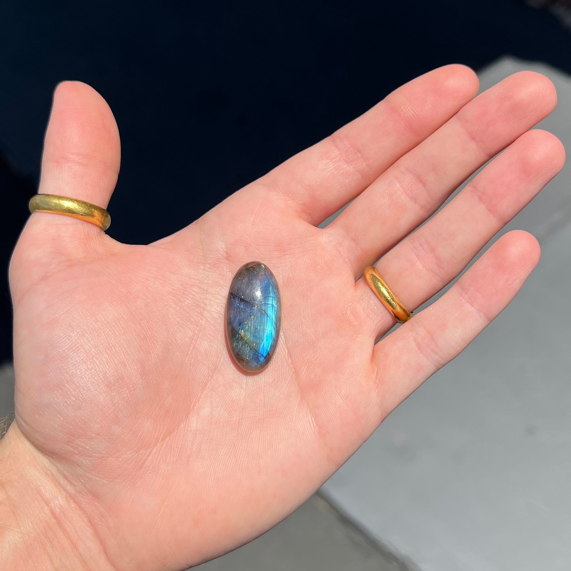 A loose, oval cabochon cut labradorite feldspar stone.  The labradorite has blue labradorescence.