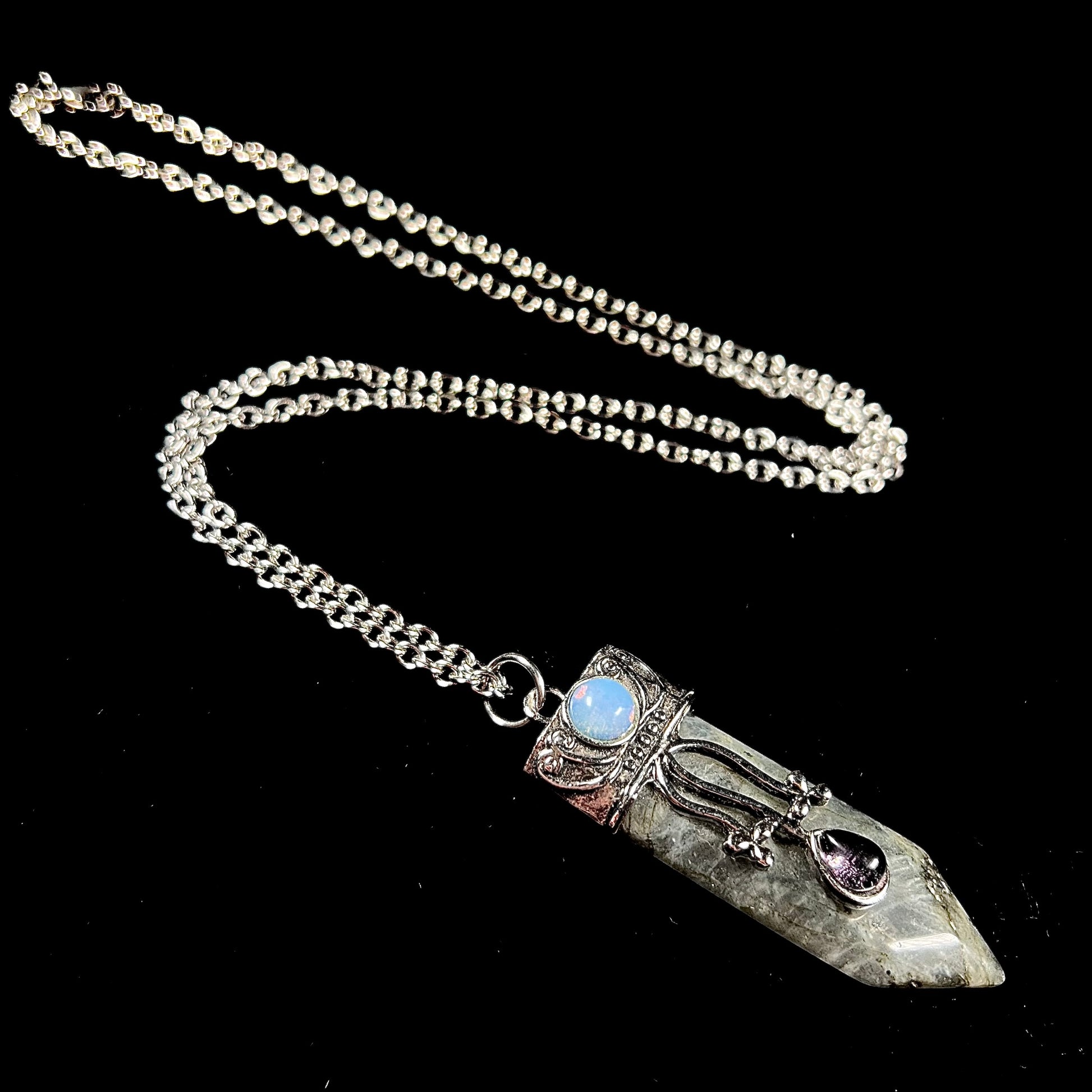 A stainless steal necklace set with a crystal shaped labradorite stone, purple glass, and an opalite accent.