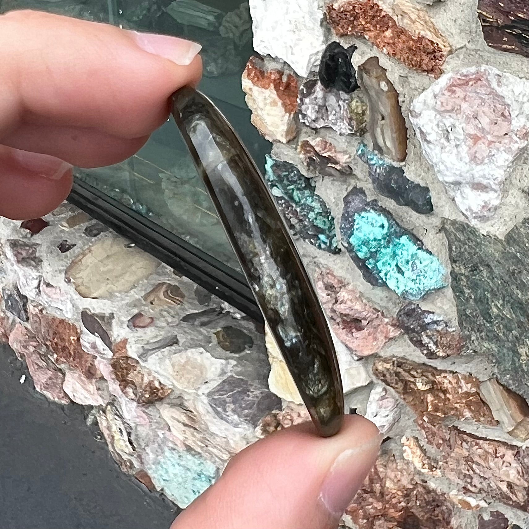 A loose, oval cabochon cut labradorite stone.  The stone is green with bright blue and yellow flashes.