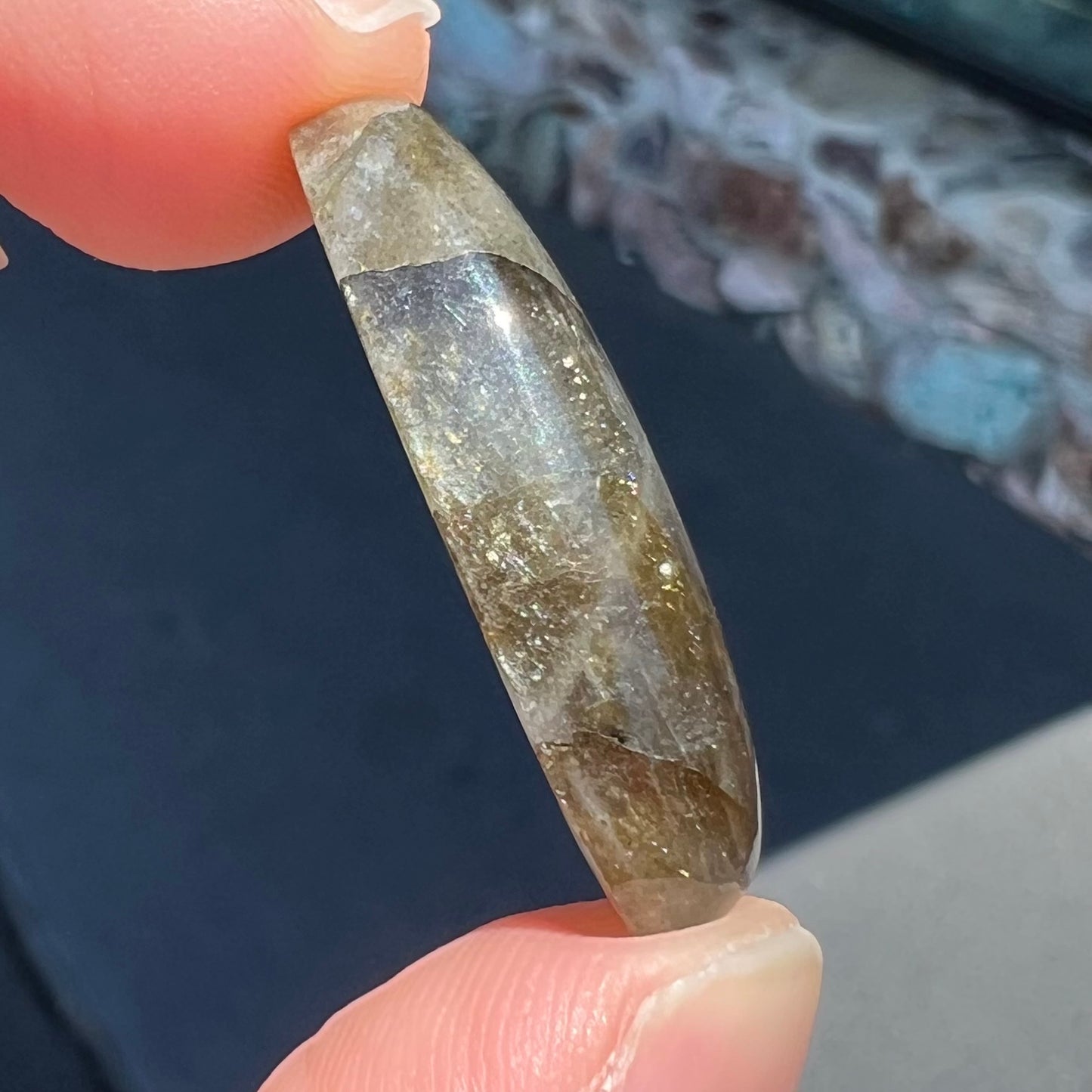 A loose, oval cabochon cut labradorite feldspar stone.  The labradorite has blue labradorescence.