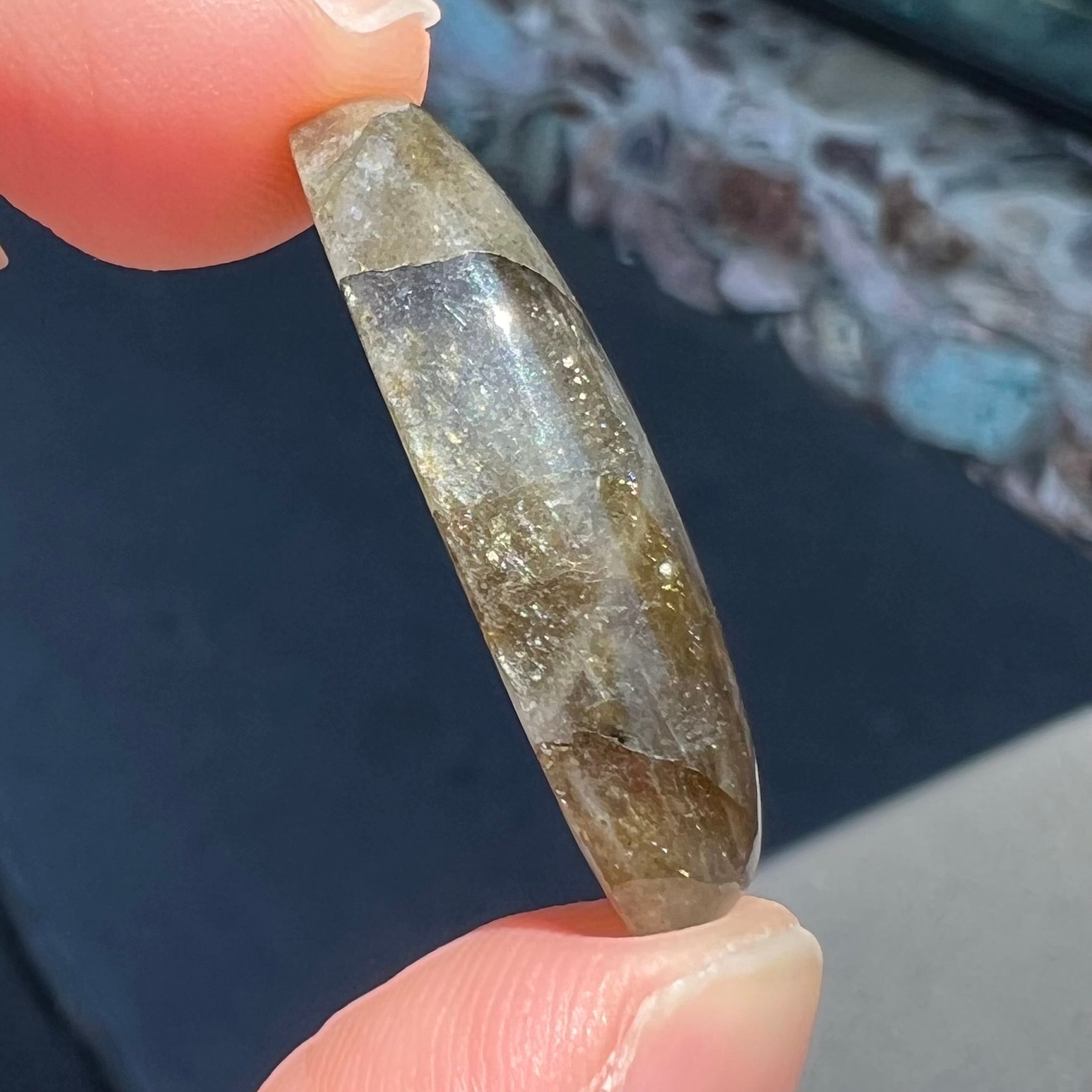 A loose, oval cabochon cut labradorite feldspar stone.  The labradorite has blue labradorescence.
