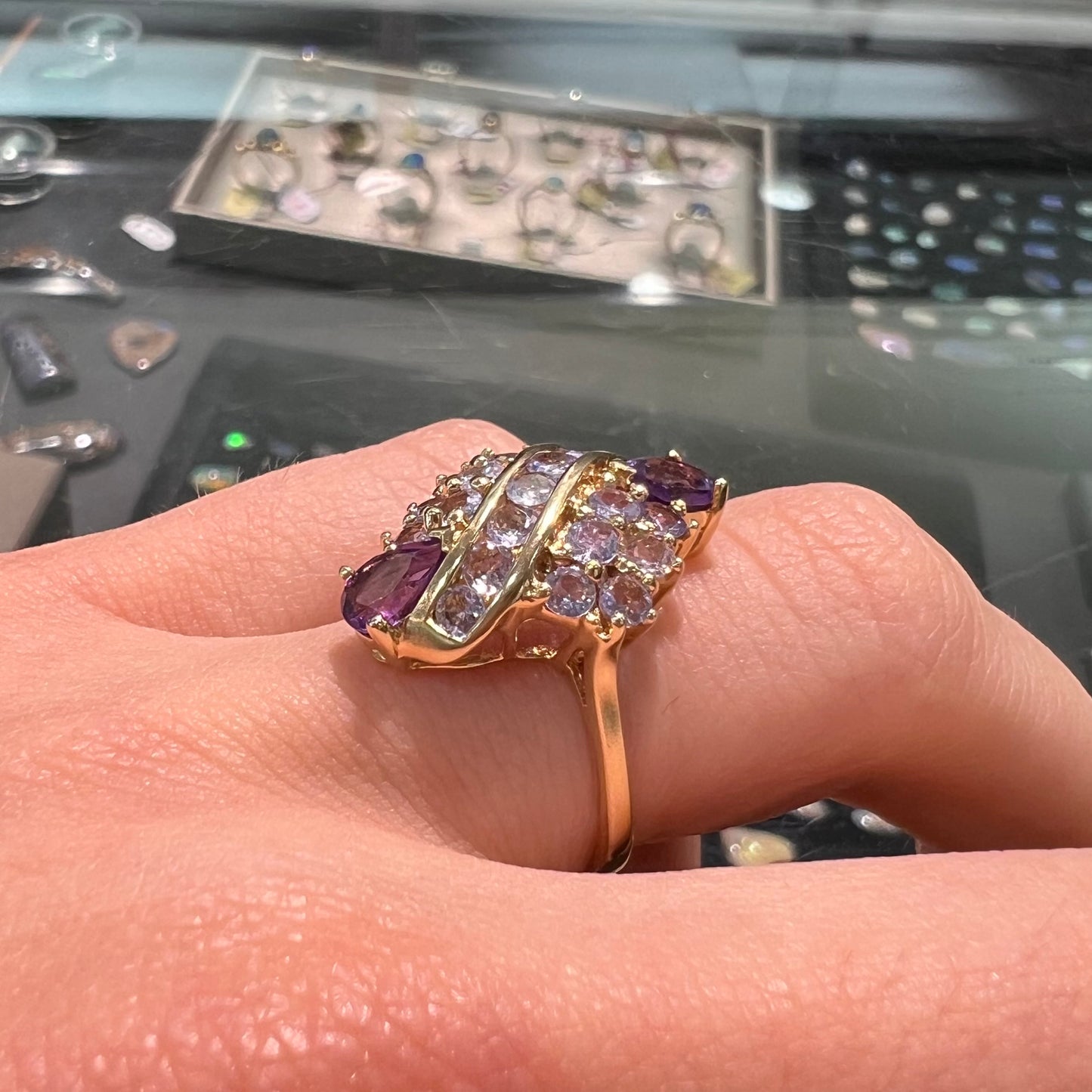 A ladies' gold ring set with a cluster of round tanzanites and two pear shaped amethyst accent stones.