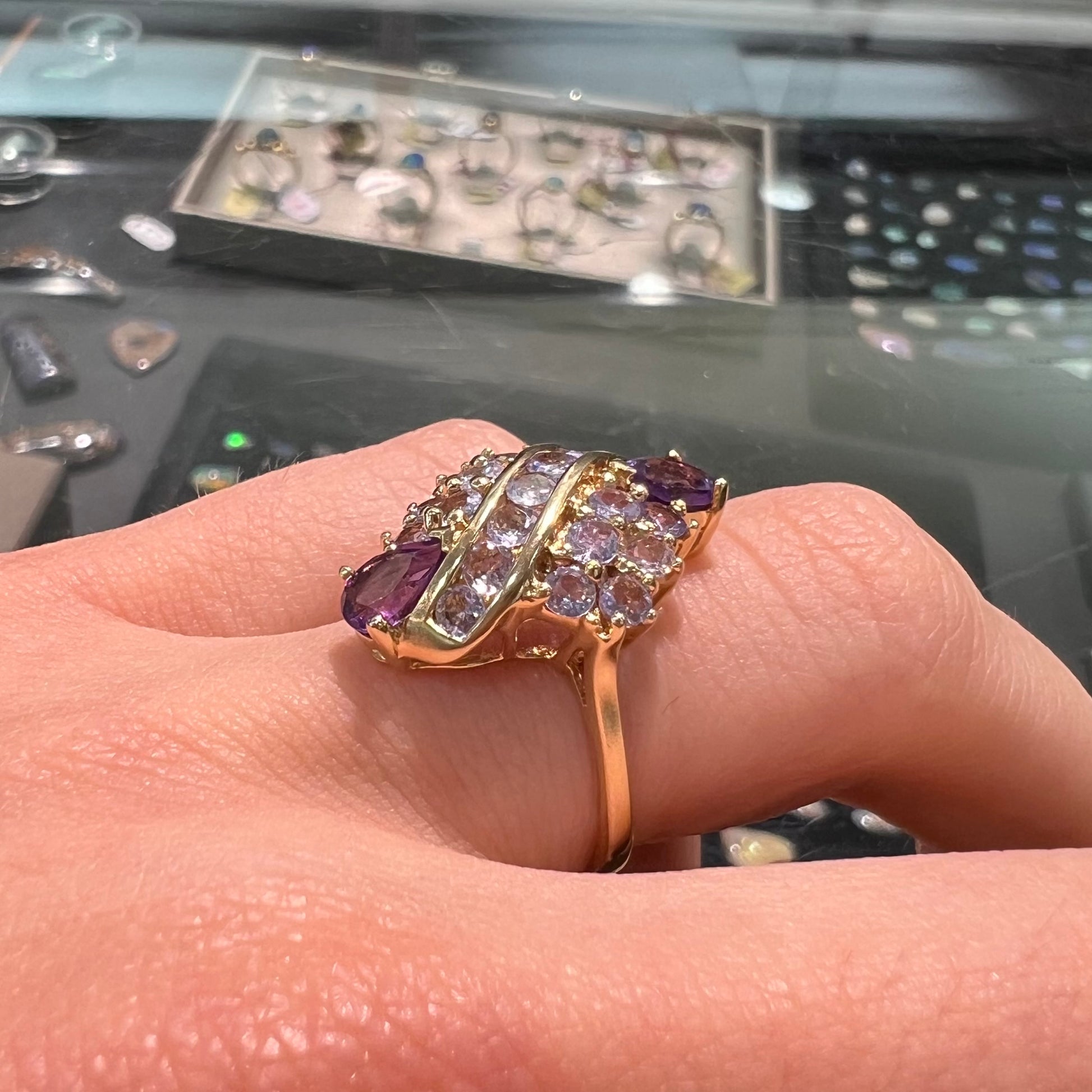 A ladies' gold ring set with a cluster of round tanzanites and two pear shaped amethyst accent stones.