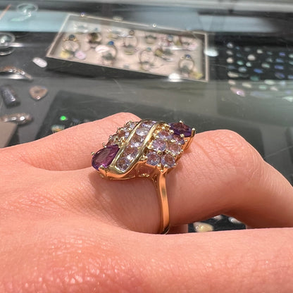 A ladies' gold ring set with a cluster of round tanzanites and two pear shaped amethyst accent stones.
