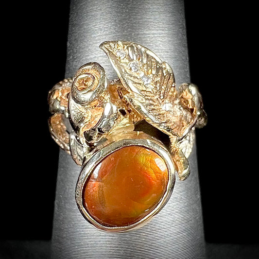 A ladies' yellow gold flower style ring set with an oval cabochon cut fire agate and diamond accents.