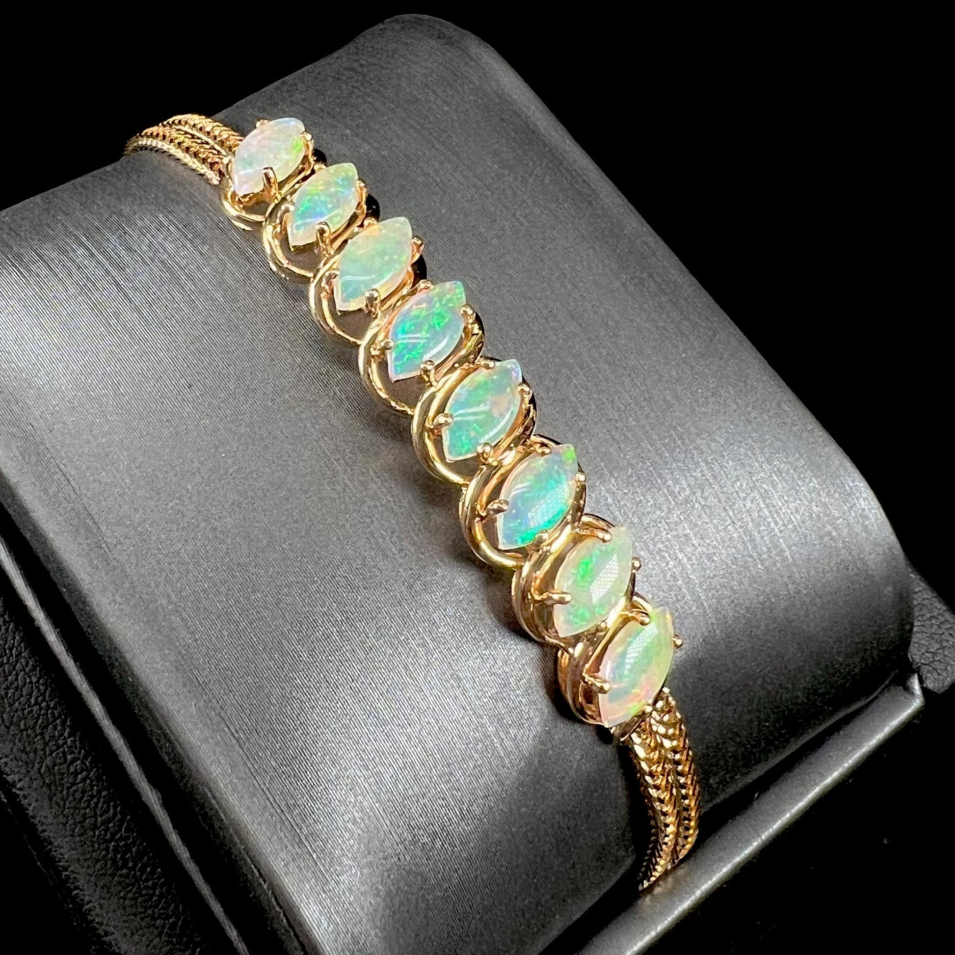 A ladies' yellow gold bracelet prong set with eight natural, marquise cabochon cut opals.