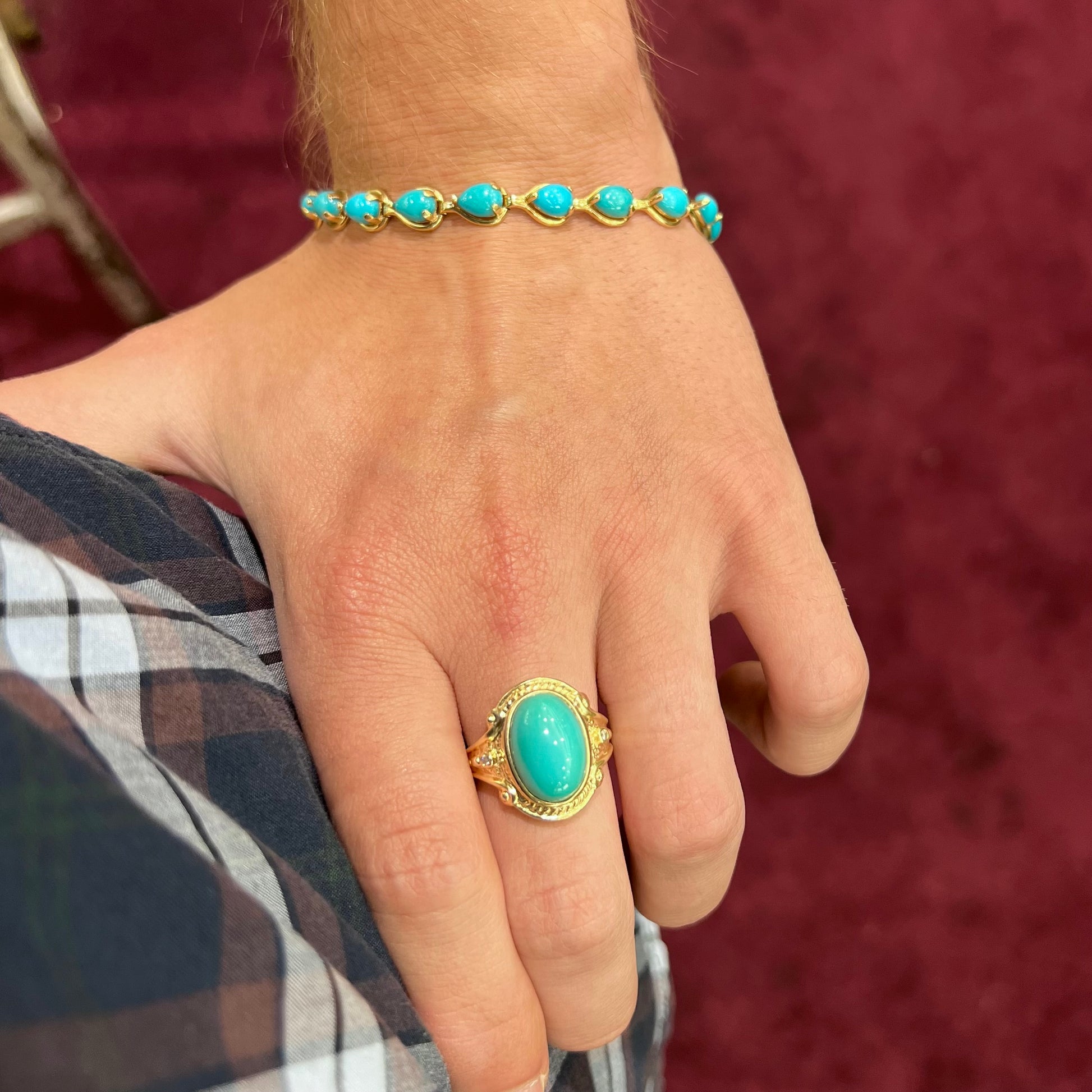 A ladies' yellow gold tennis style bracelet set with pear cabochon shaped natural Sleeping Beauty turquoise stones.