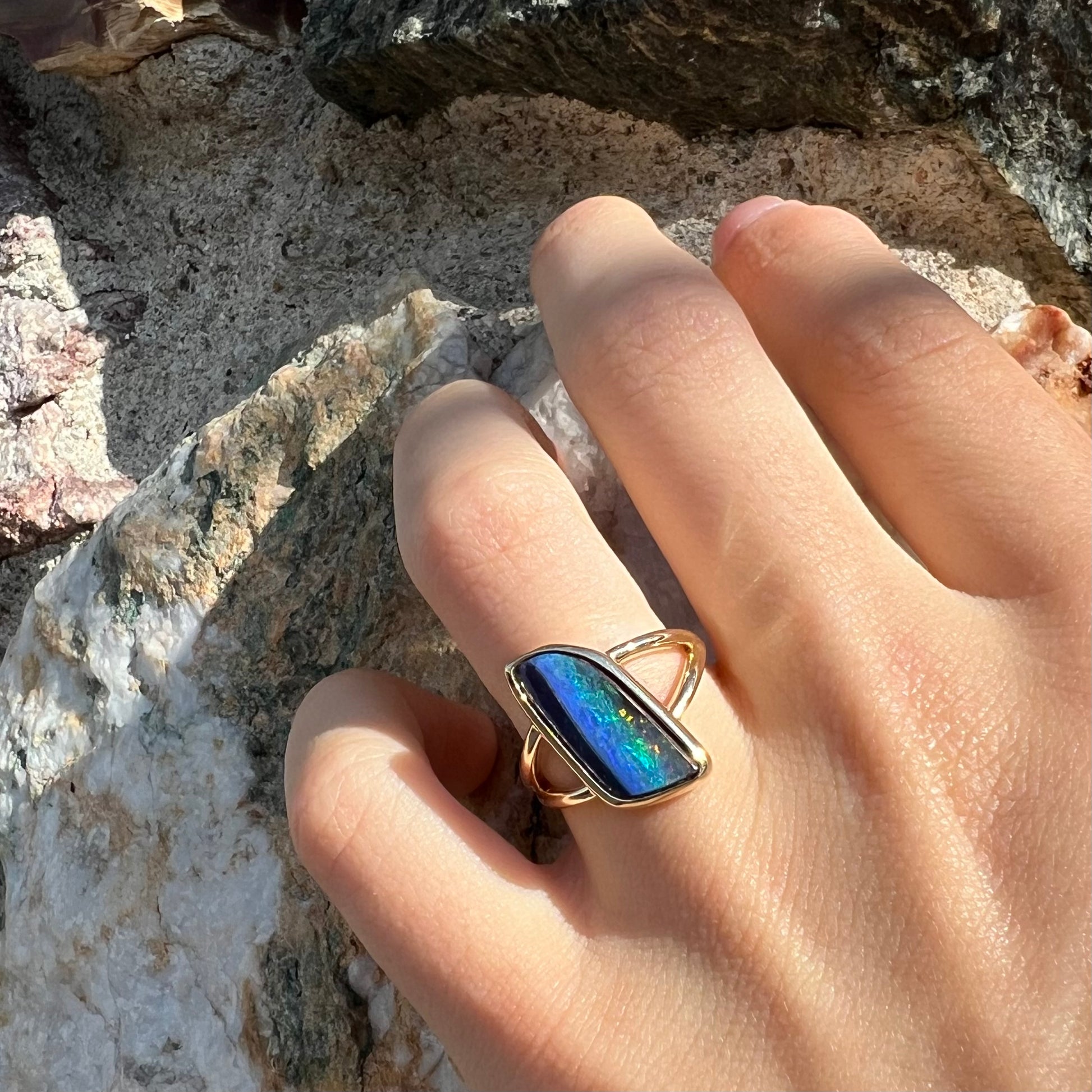 A ladies' split shank gold ring bezel set with a natural, Australian black boulder opal.
