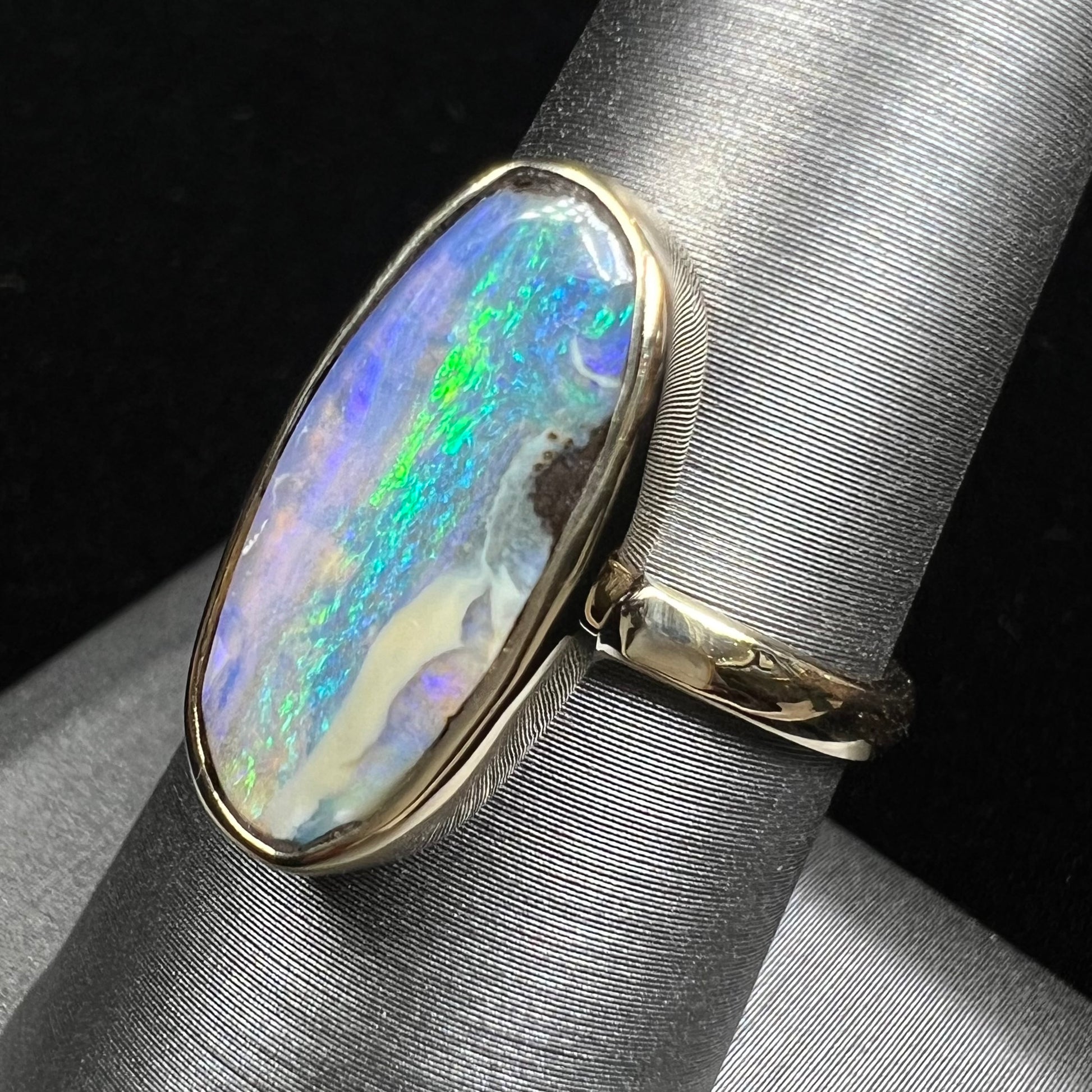 Ladies' yellow gold solitaire ring bezel set with a natural green striped boulder opal from Quilpie, Australia.