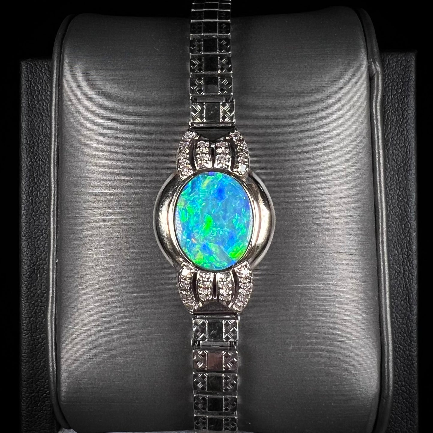 A ladies' art deco style white gold and stainless steel bracelet set with a natural black opal doublet and diamonds.