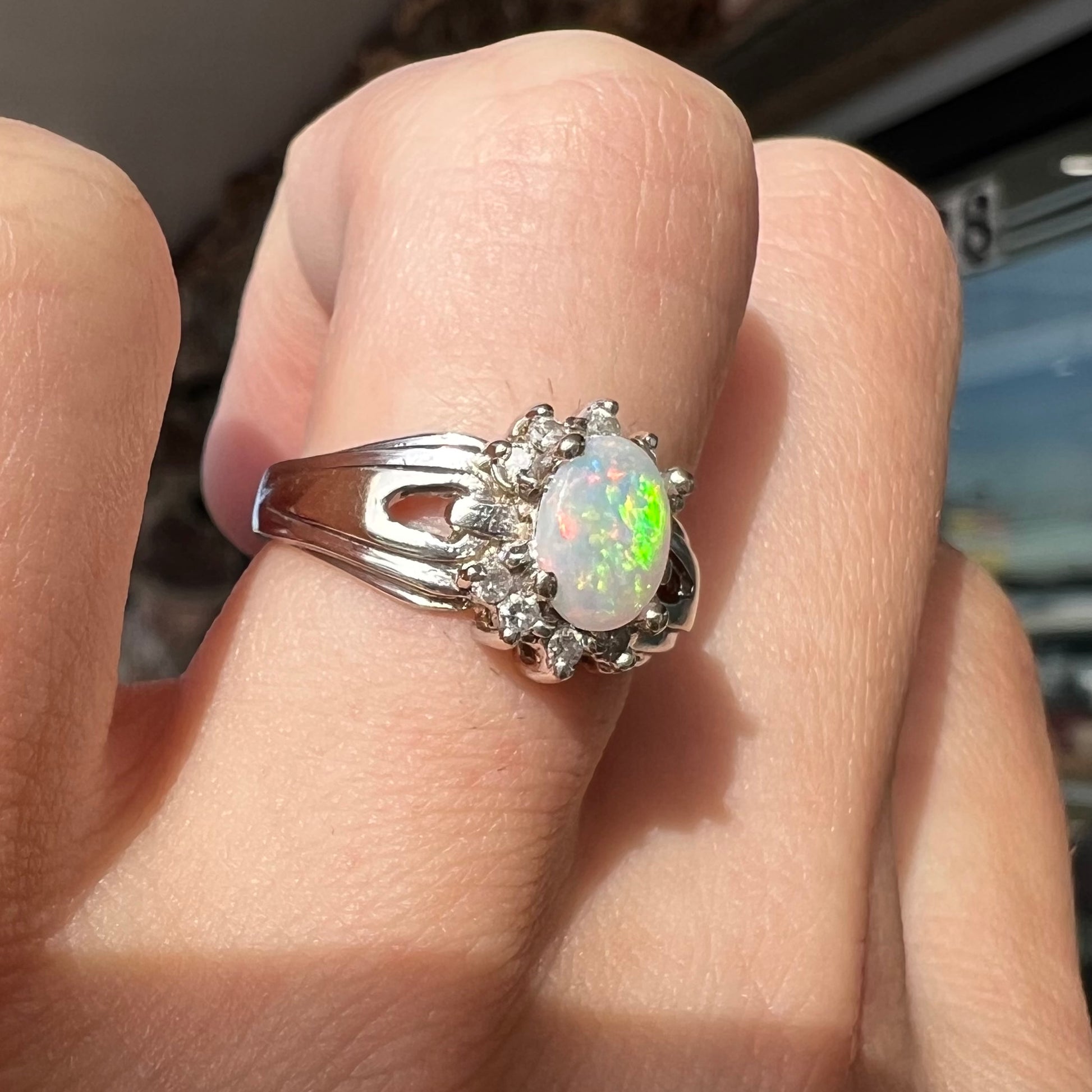 A ladies' white gold ring set with a halo of diamonds and an oval cabochon cut Australian opal.