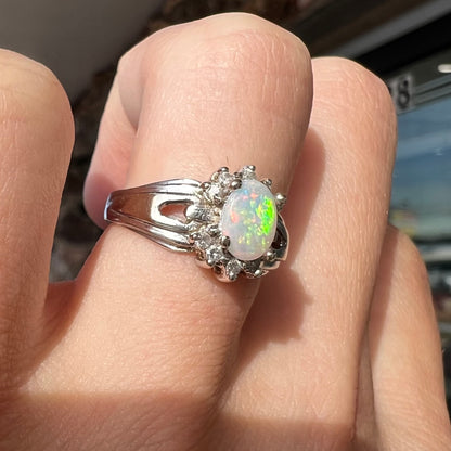A ladies' white gold ring set with a halo of diamonds and an oval cabochon cut Australian opal.