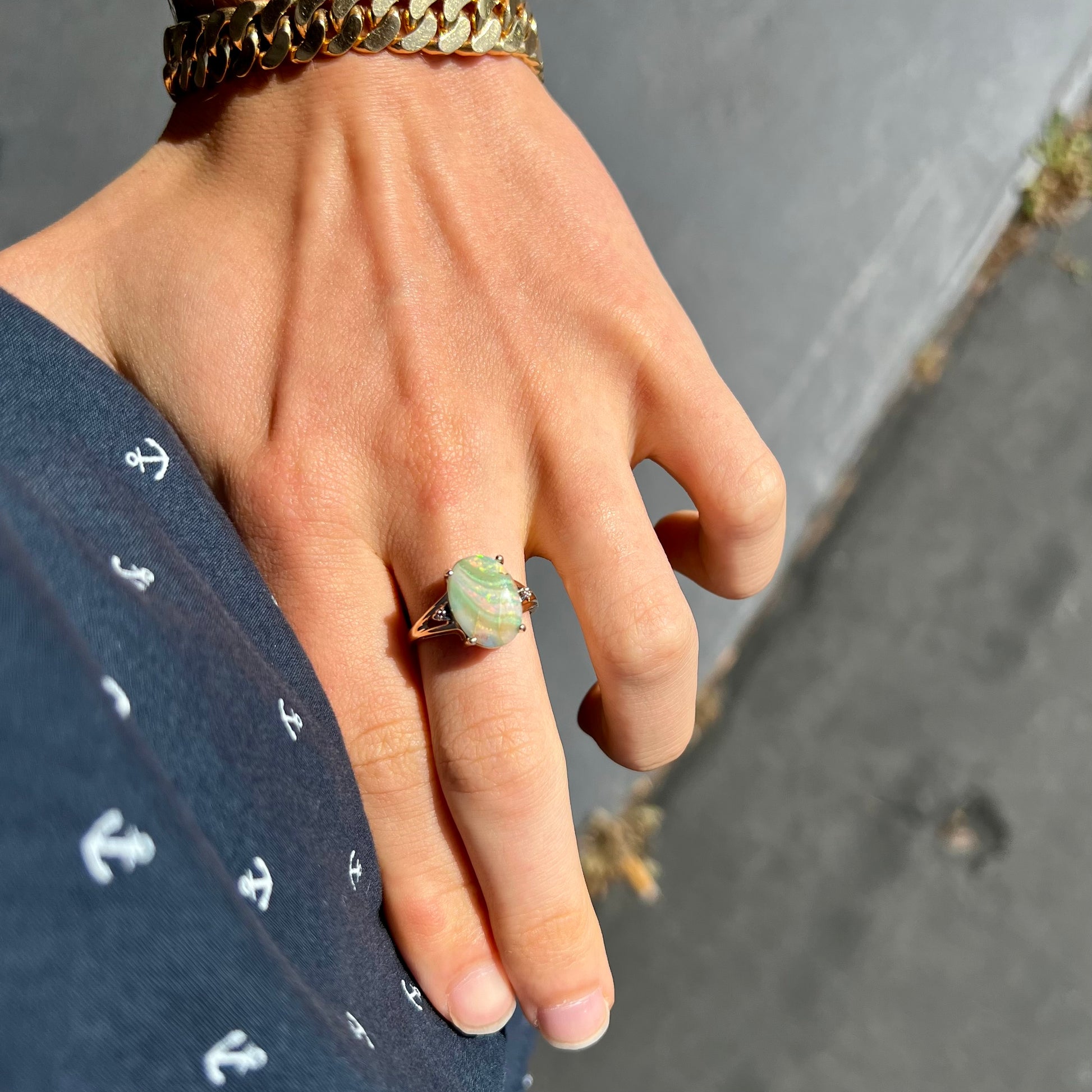 A ladies' Australian boulder opal ring set in yellow gold with diamond accents.  The opal shimmers green and pink and has fissure inclusions.