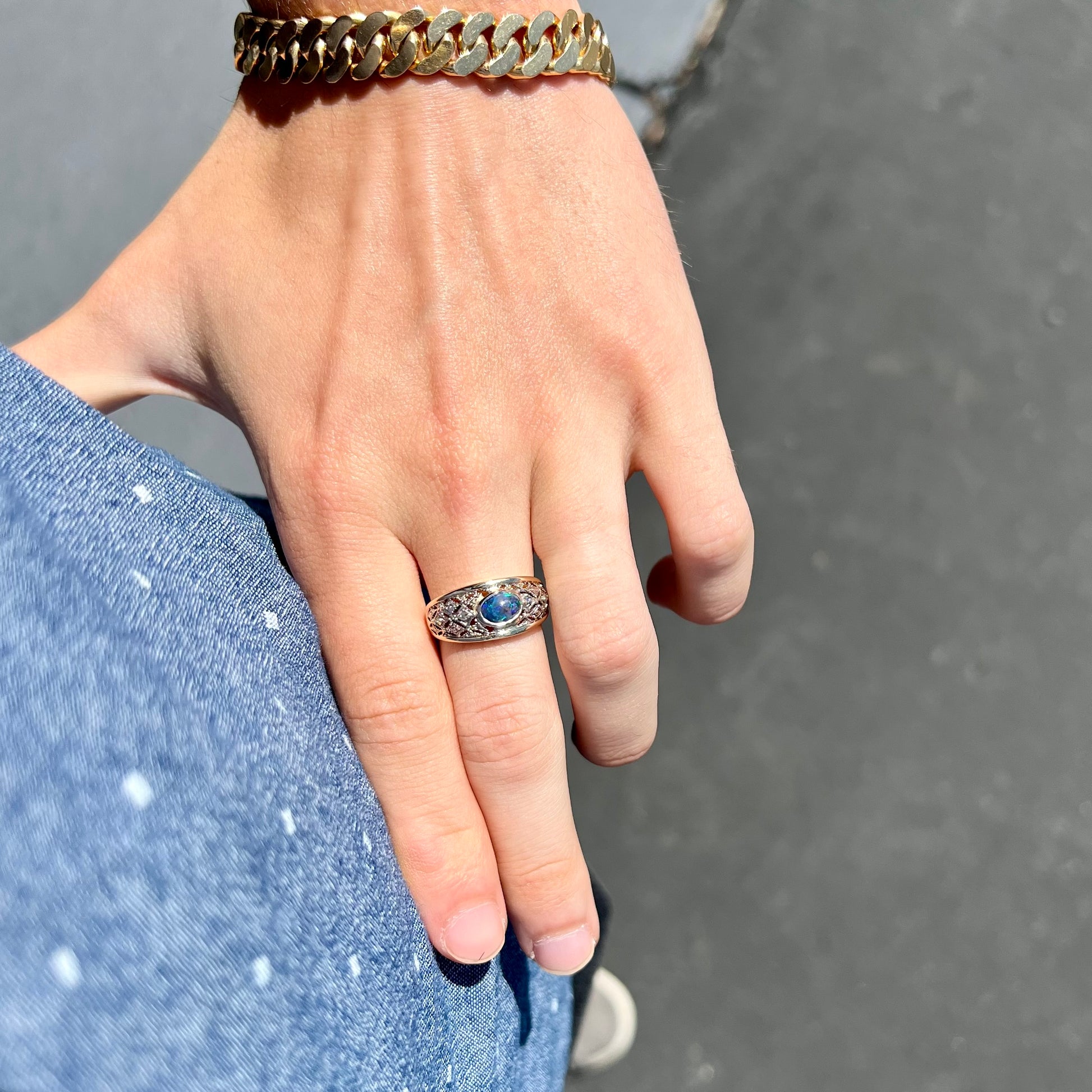 A ladies' yellow gold filigree style ring set with a natural black opal and diamond accents.