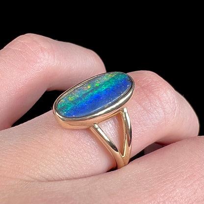 A ladies' yellow gold split shank solitaire ring set with a natural Australian black boulder opal.