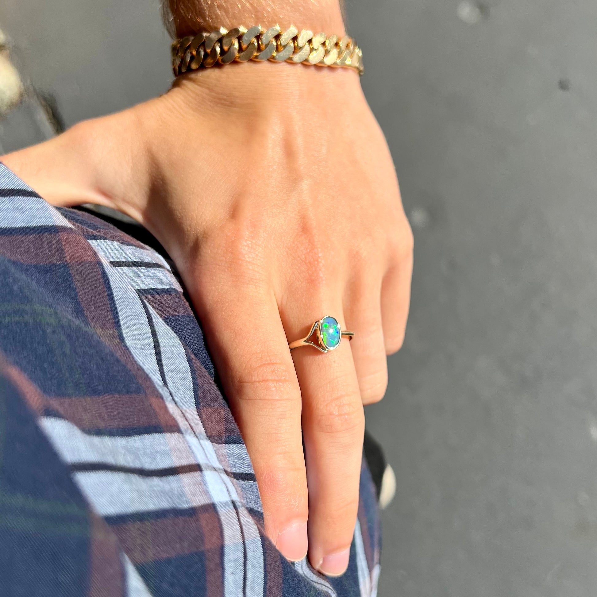 A ladies' oval cut black crystal opal solitaire ring handmade with a single split shank in yellow gold.
