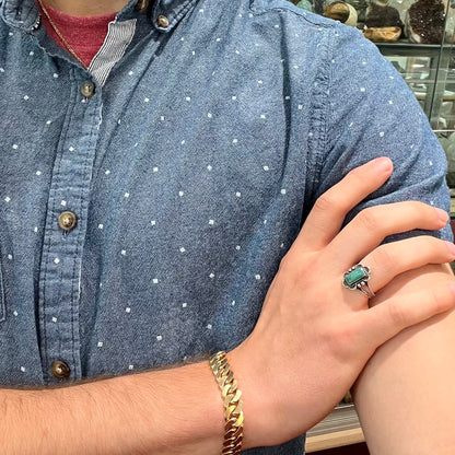 A ladies' silver ring stamped with Southwest style designs and set with a rectangular cabochon cut Royston turquoise stone.