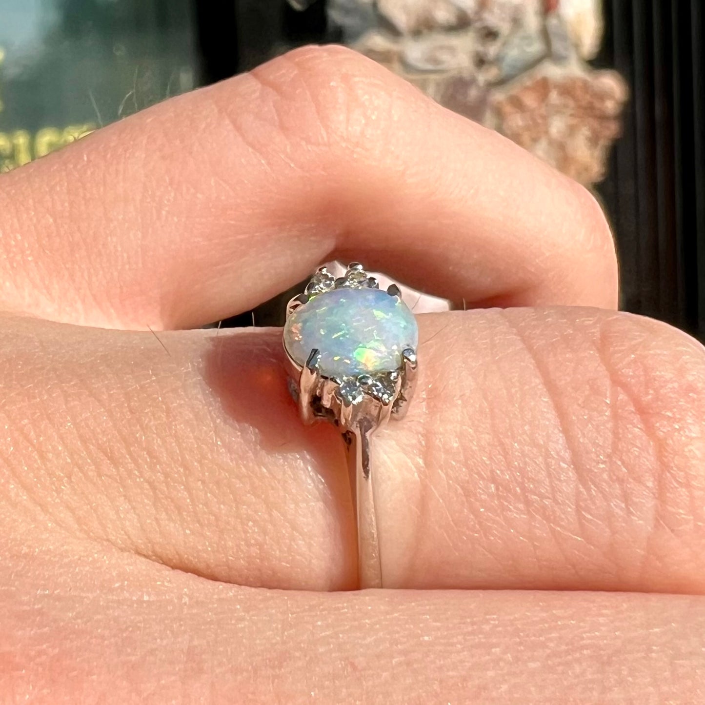 A ladies' white gold opal and diamond ring.  The opal shines orange, yellow, and green colors.