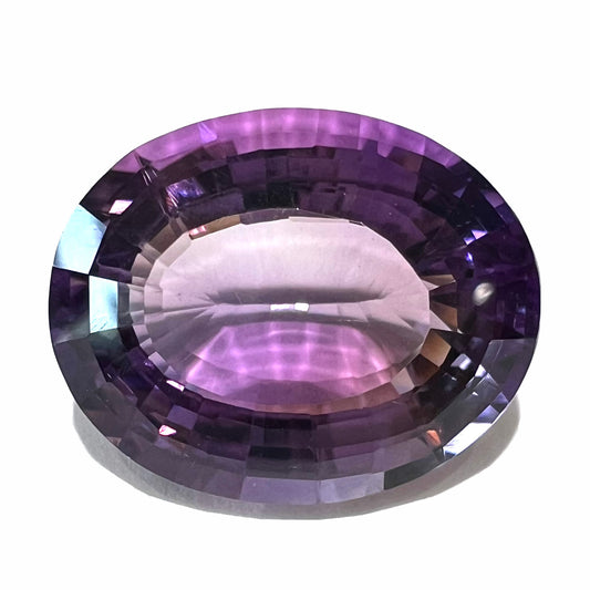 A loose, modified oval cut amethyst gemstone.  The stone is a large size.