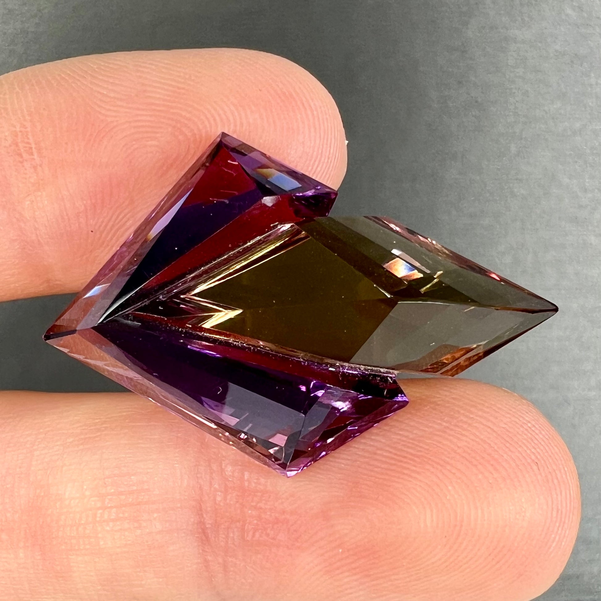 A loose, faceted fantasy cut ametrine gemstone cut by famous carver, Arthur Lee Anderson.