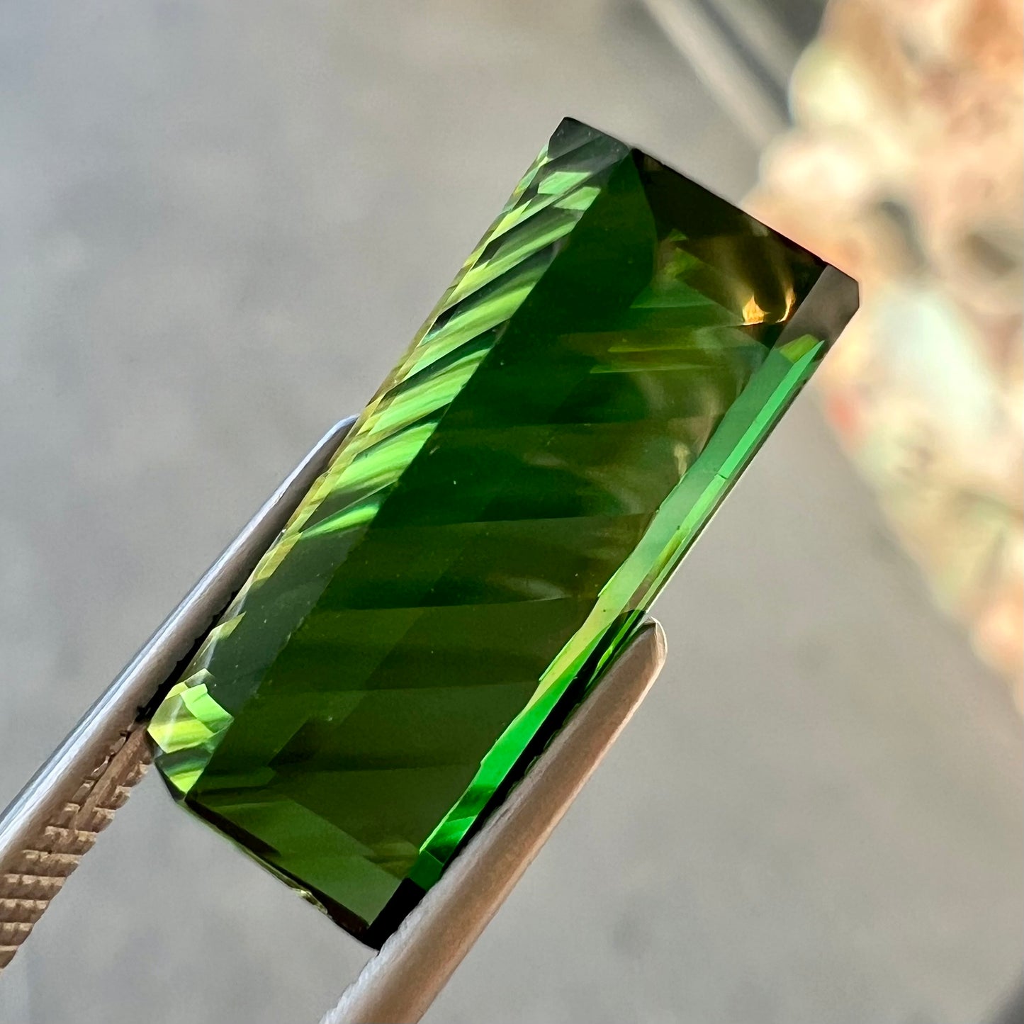 A loose, rectangular laser cut green tourmaline gemstone.