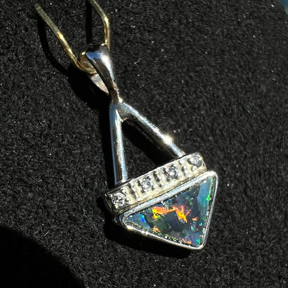 A white gold pendant and earrings set mounted with triangle cut natural black opals and diamonds.