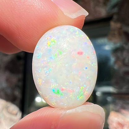 An oval cabochon cut white opal.  The opal has an eye-visible natural fissure inclusion.