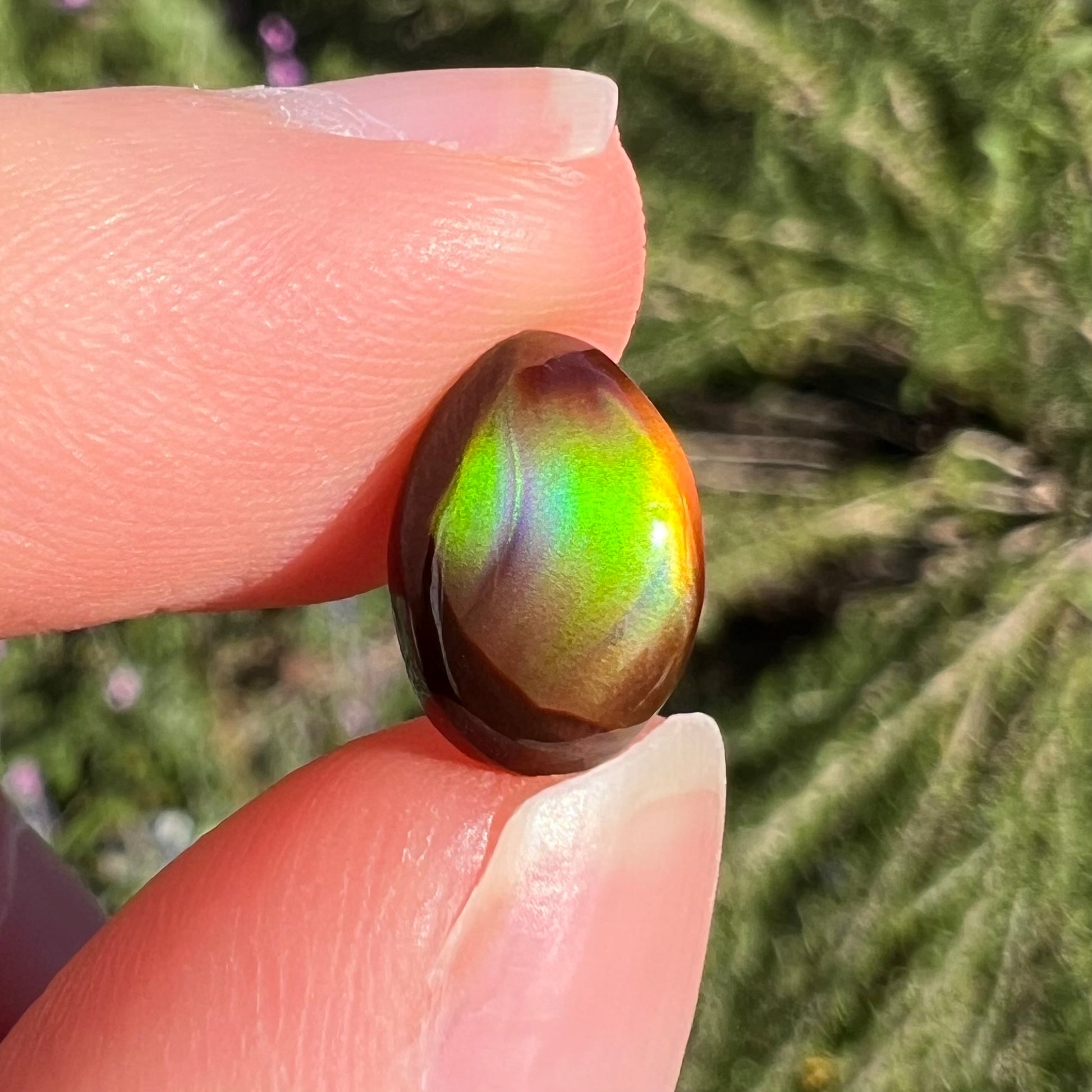 A loose, 3.38ct, pear shaped Mexican fire agate stone.  The stone shines a vivid, bright green color with a purple streak.