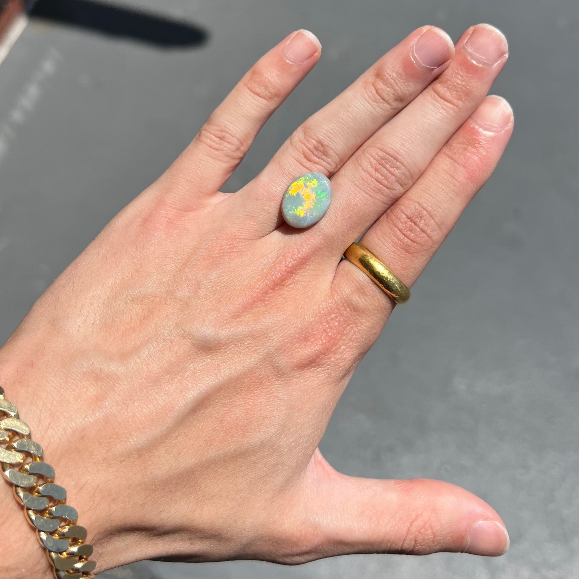 A loose, oval cut light opal stone from Mintabie, Australia.  The stone shows dull orange and green colors.