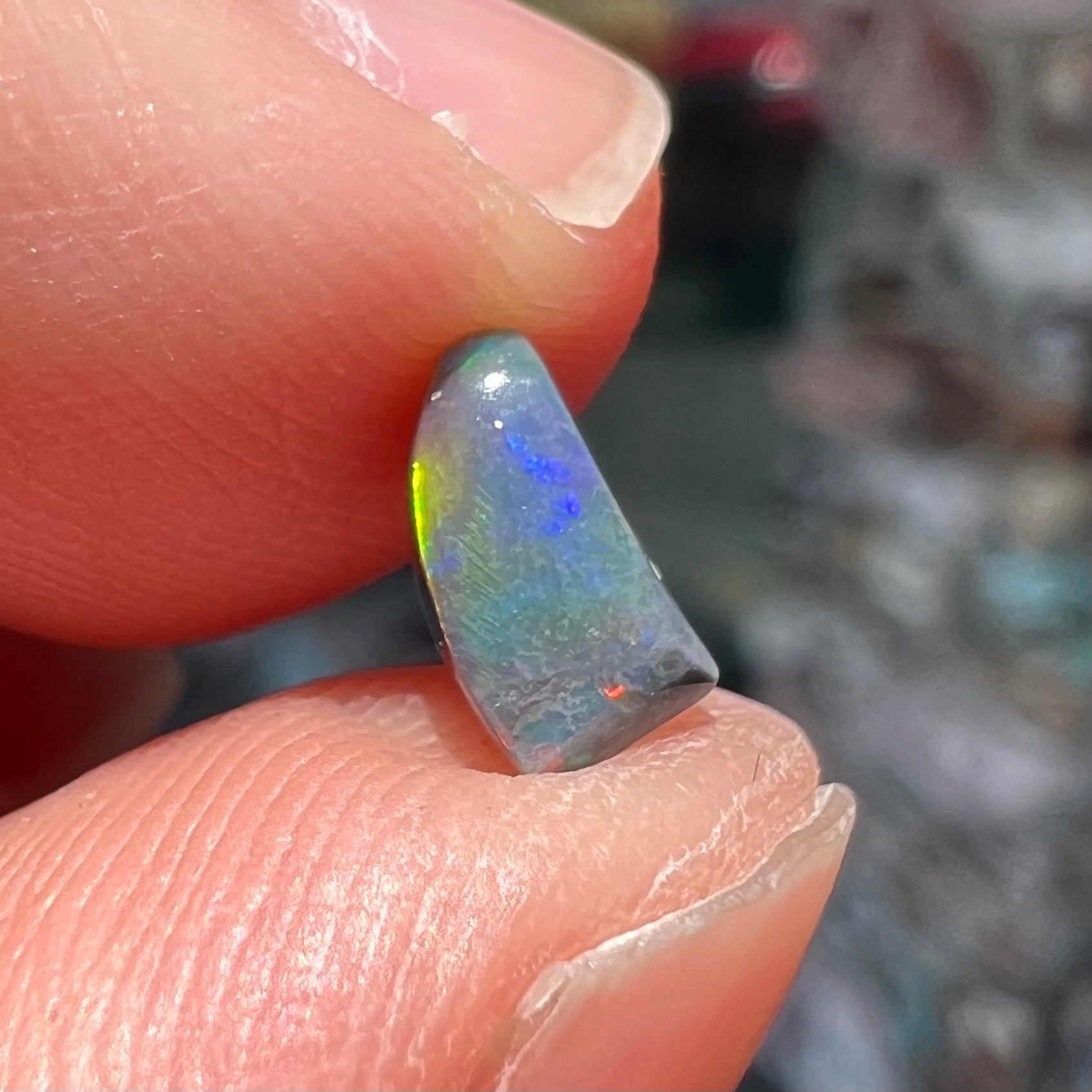 A freeform shaped black opal stone from Lightning Ridge, Australia.