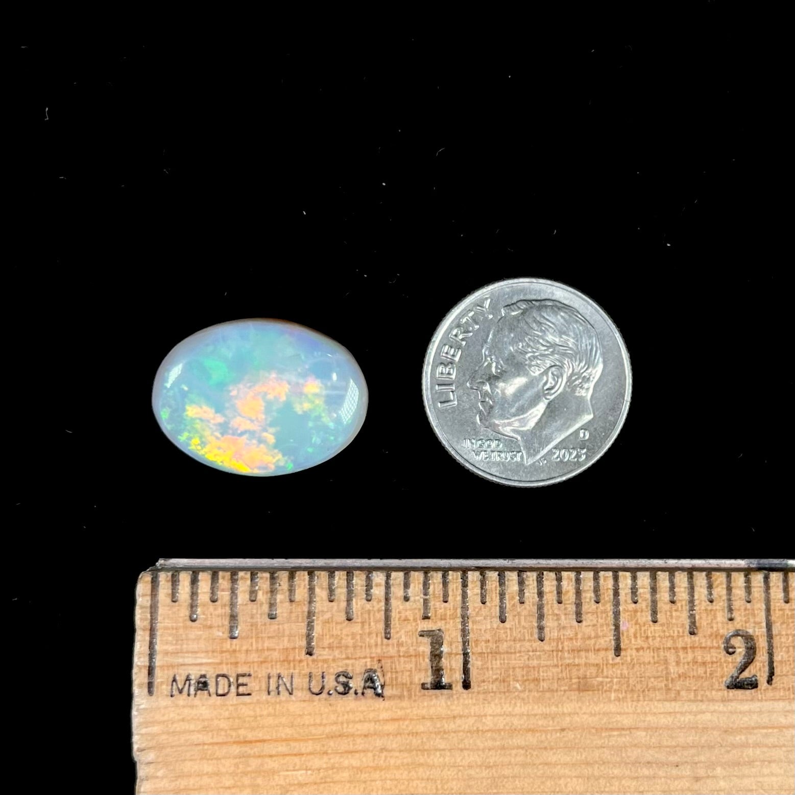A loose, oval cut light opal stone from Mintabie, Australia.  The stone shows dull orange and green colors.