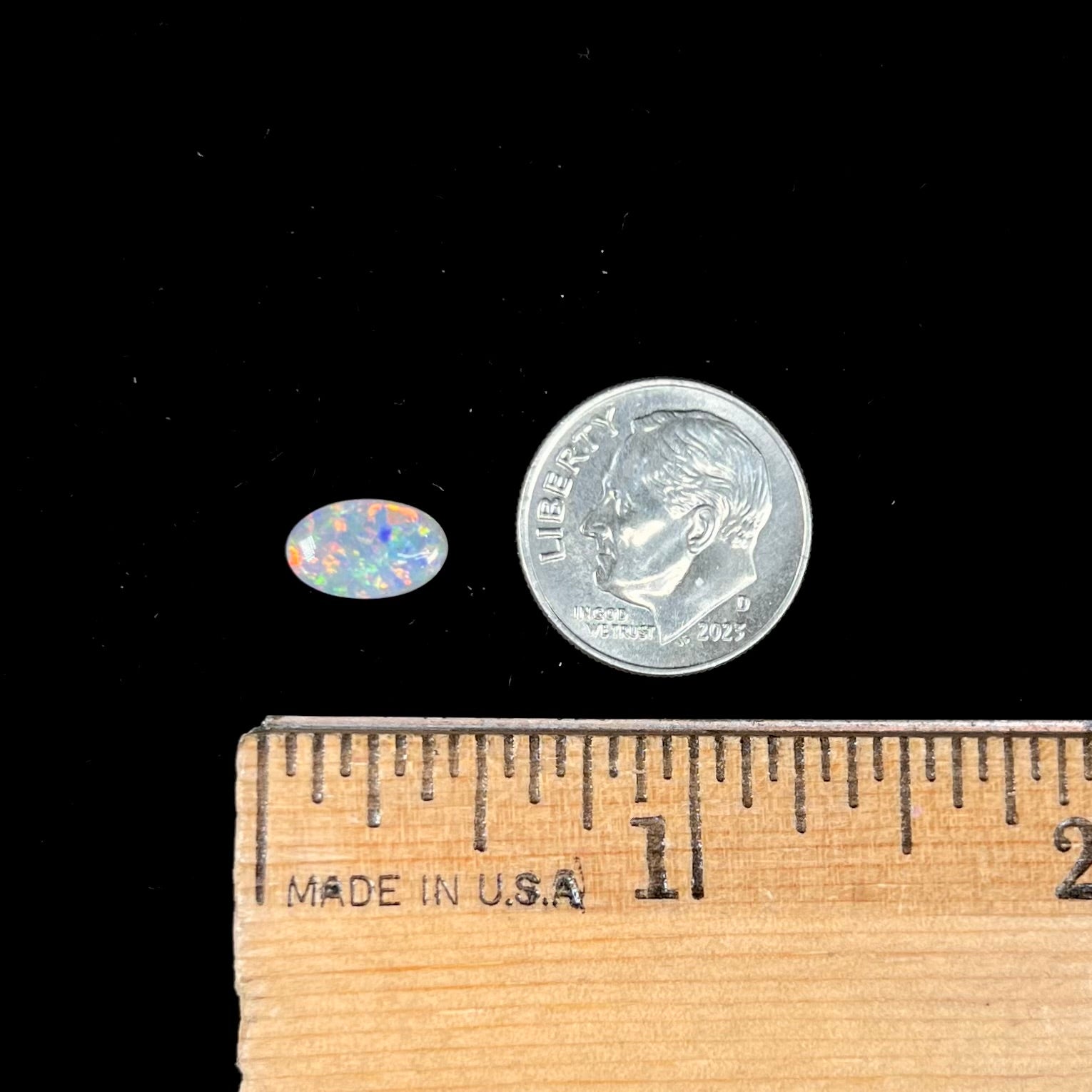 A loose, oval cabochon cut semi-black opal stone from Lightning Ridge, Australia.