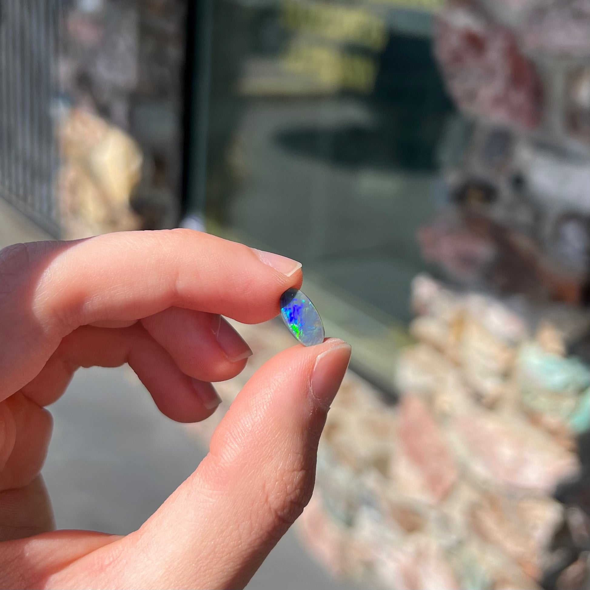 A loose, oval shaped black opal stone from Lightning Ridge, Australia.  The opal plays bright green and blue colors.