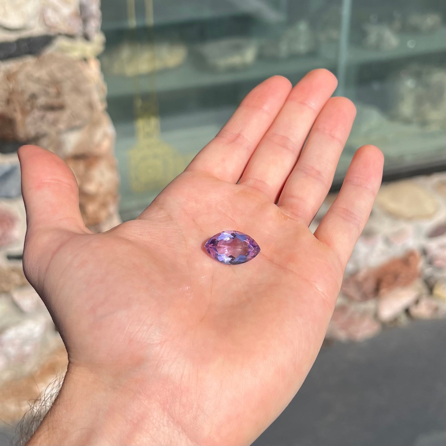 A loose marquise cut amethyst gemstone.  The stone is a light purple color and has scratches along the surface.