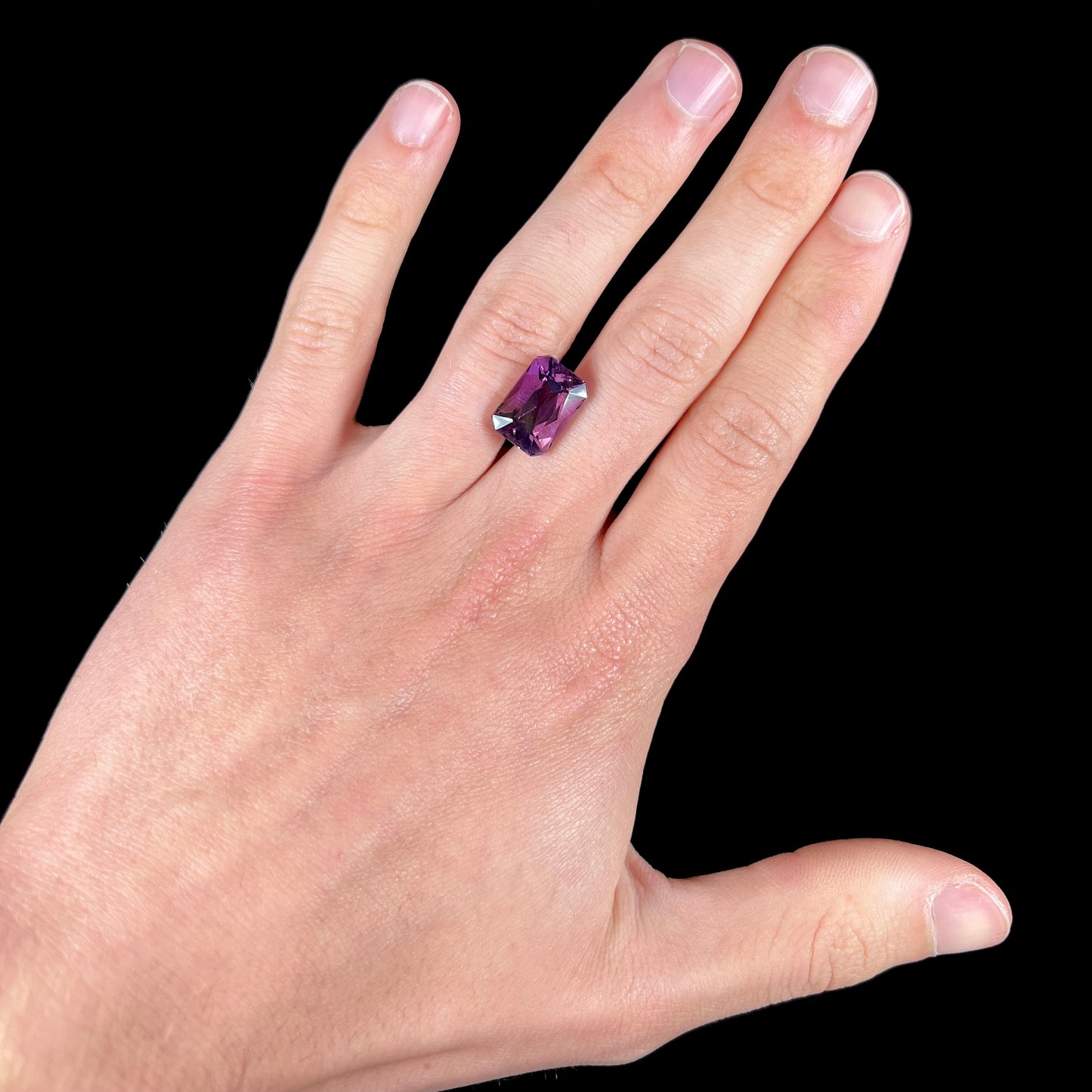 A loose, modified radiant cut amethyst stone.