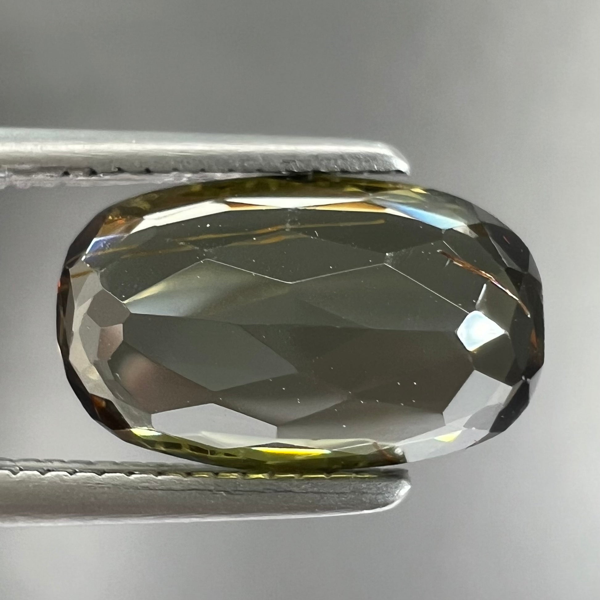 A modified oval cut andalusite gemstone.  The stone has eye-visible rutile inclusions.