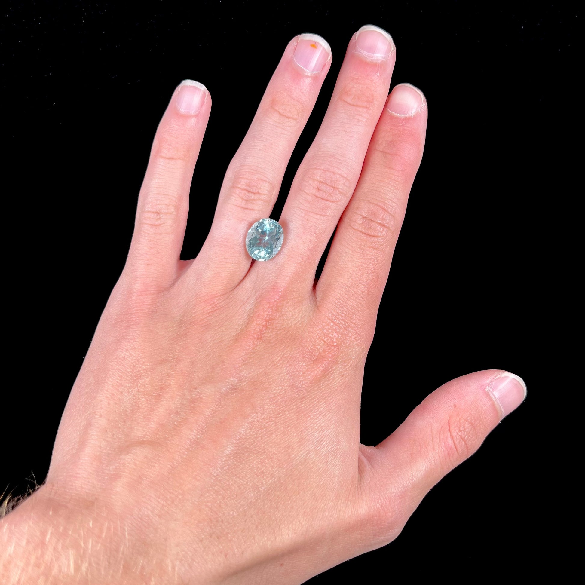 A loose, faceted oval cut aquamarine gemstone from Brazil.  The stone is greenish blue color.