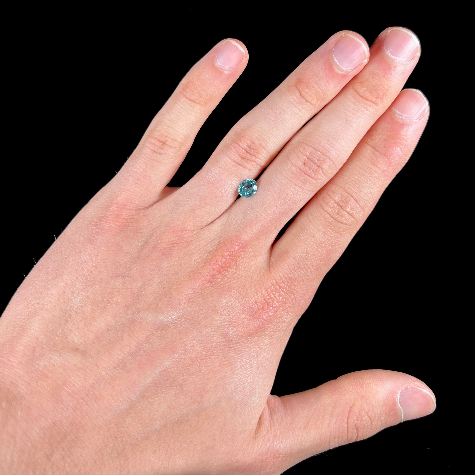 A loose, faceted oval cut blue zircon gemstone.