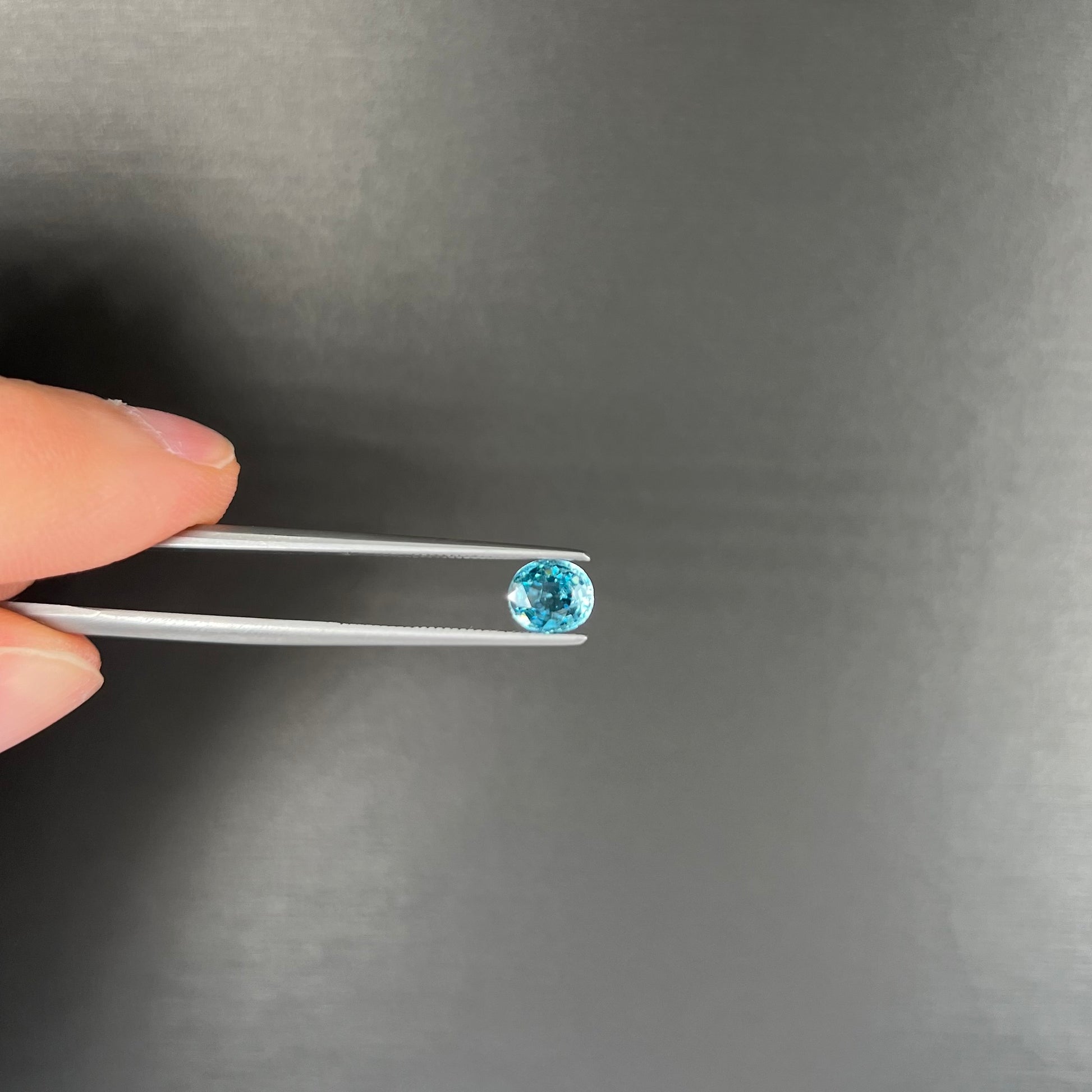 A loose, faceted oval cut blue zircon gemstone.
