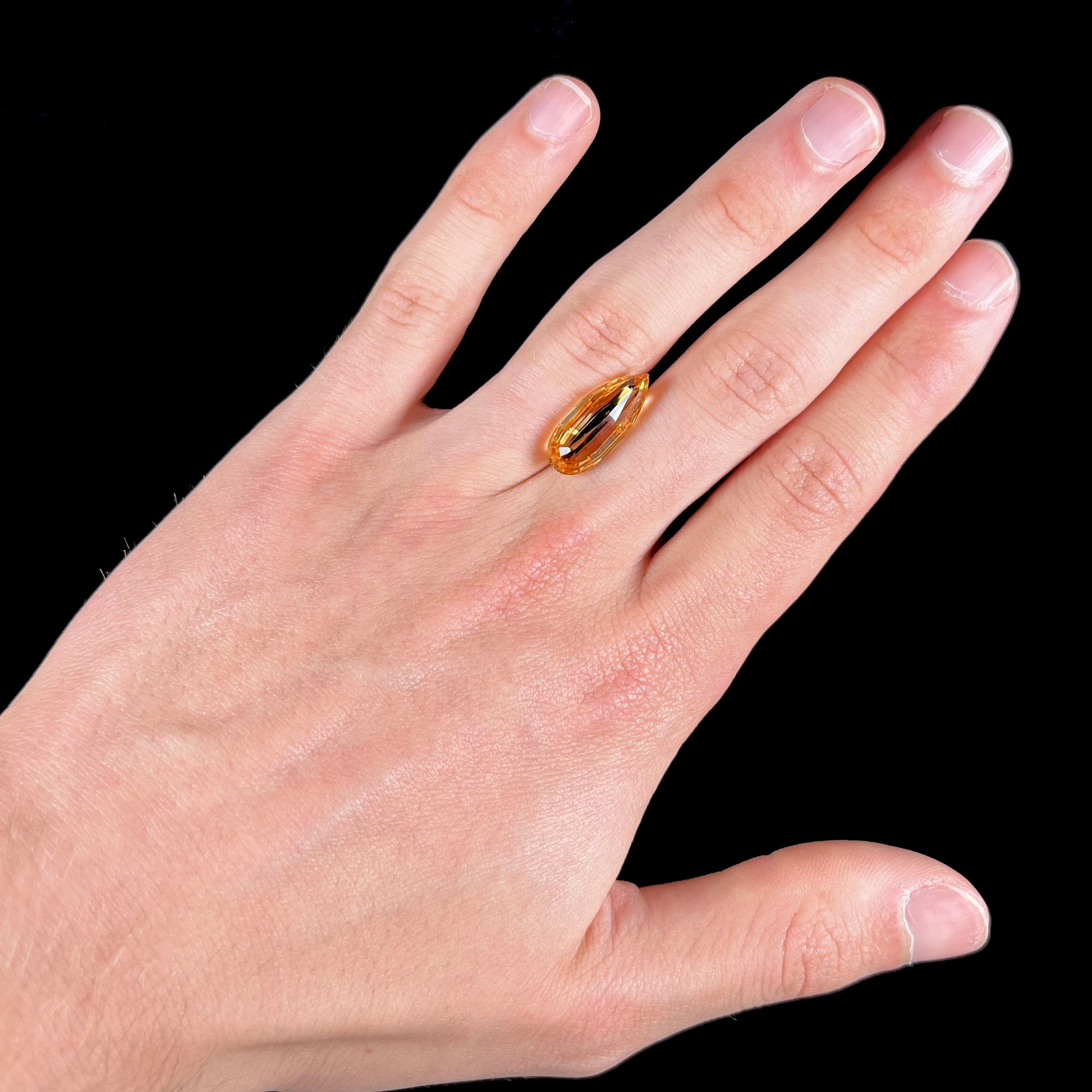 A loose, faceted briolette cut citrine gemstone.