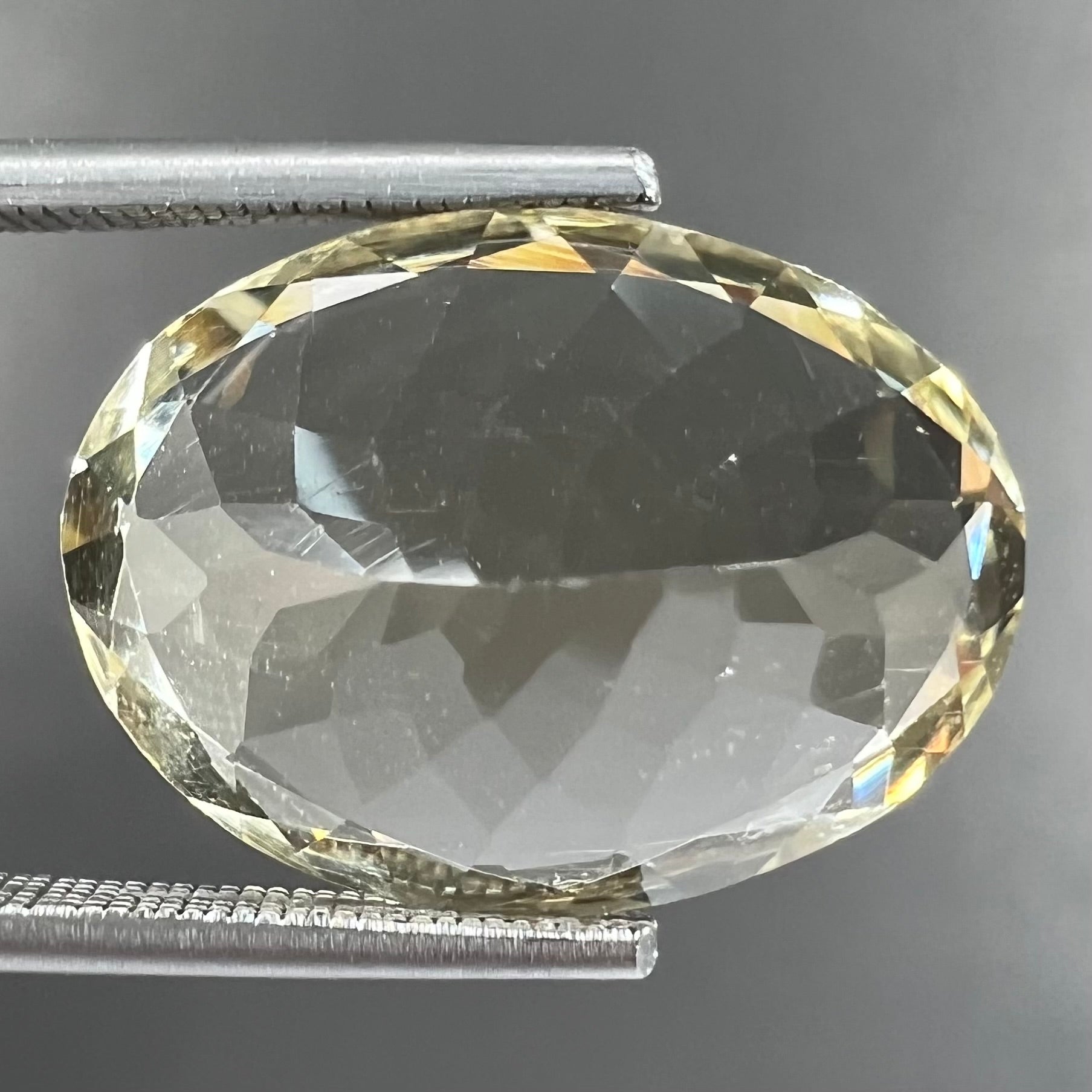 A loose, faceted oval cut citrine stone.  The stone is light yellow in color.