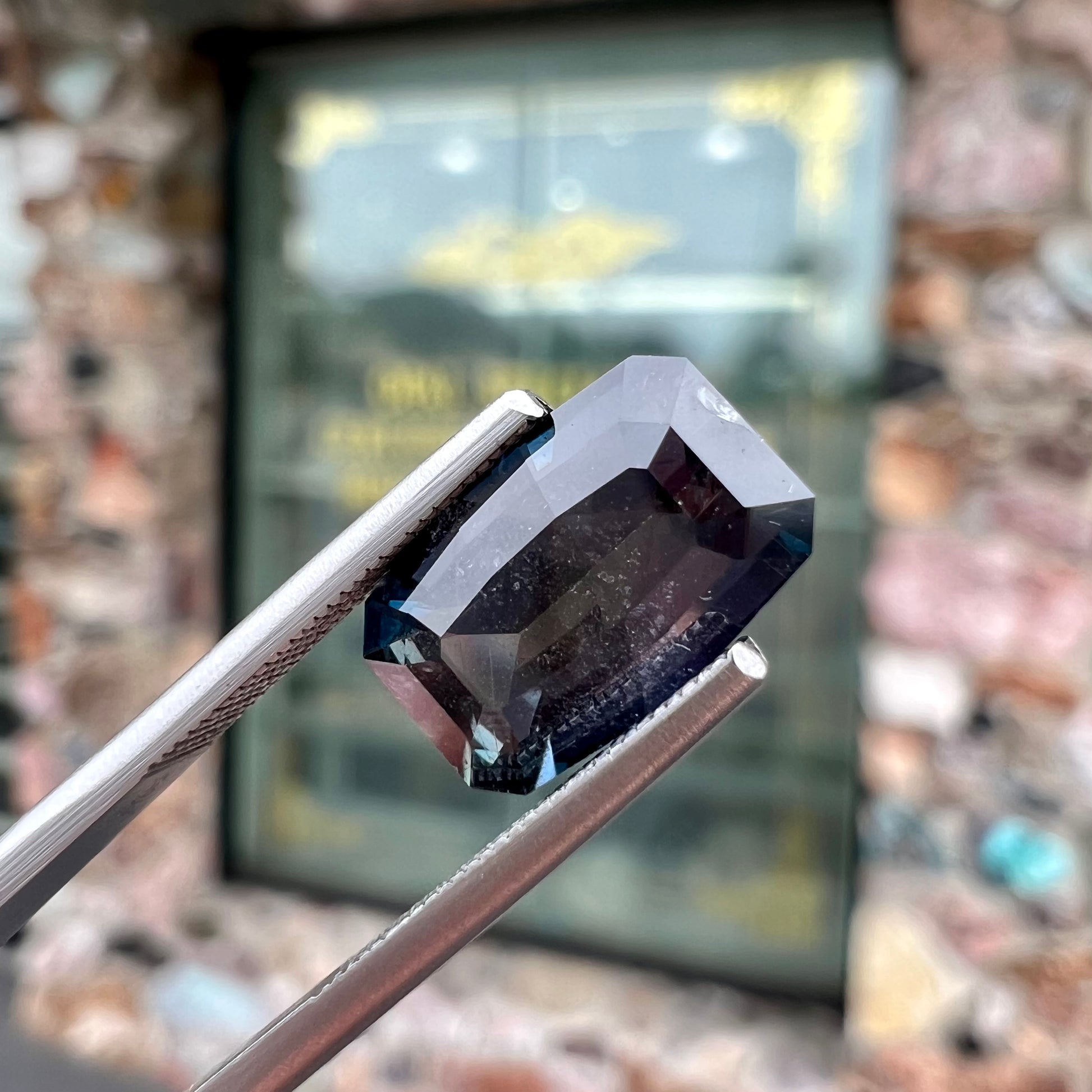 A loose, modified emerald cut, natural color change sapphire stone.  The stone shifts from black to blue to purple to green.