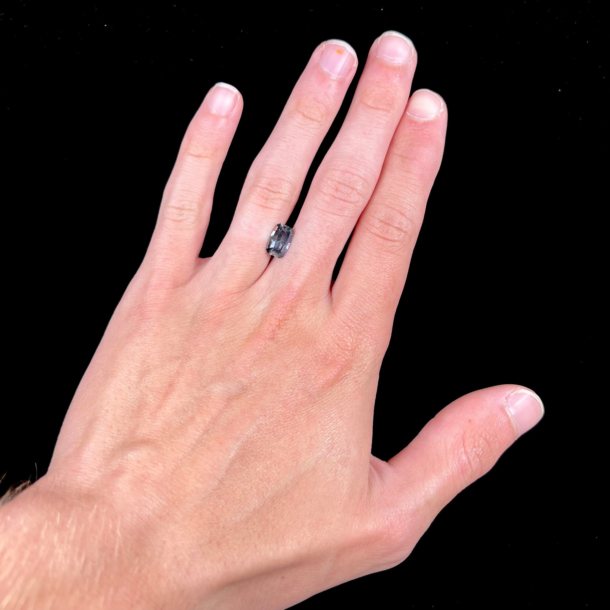 A loose, modified emerald cut, natural color change sapphire stone.  The stone shifts from black to blue to purple to green.