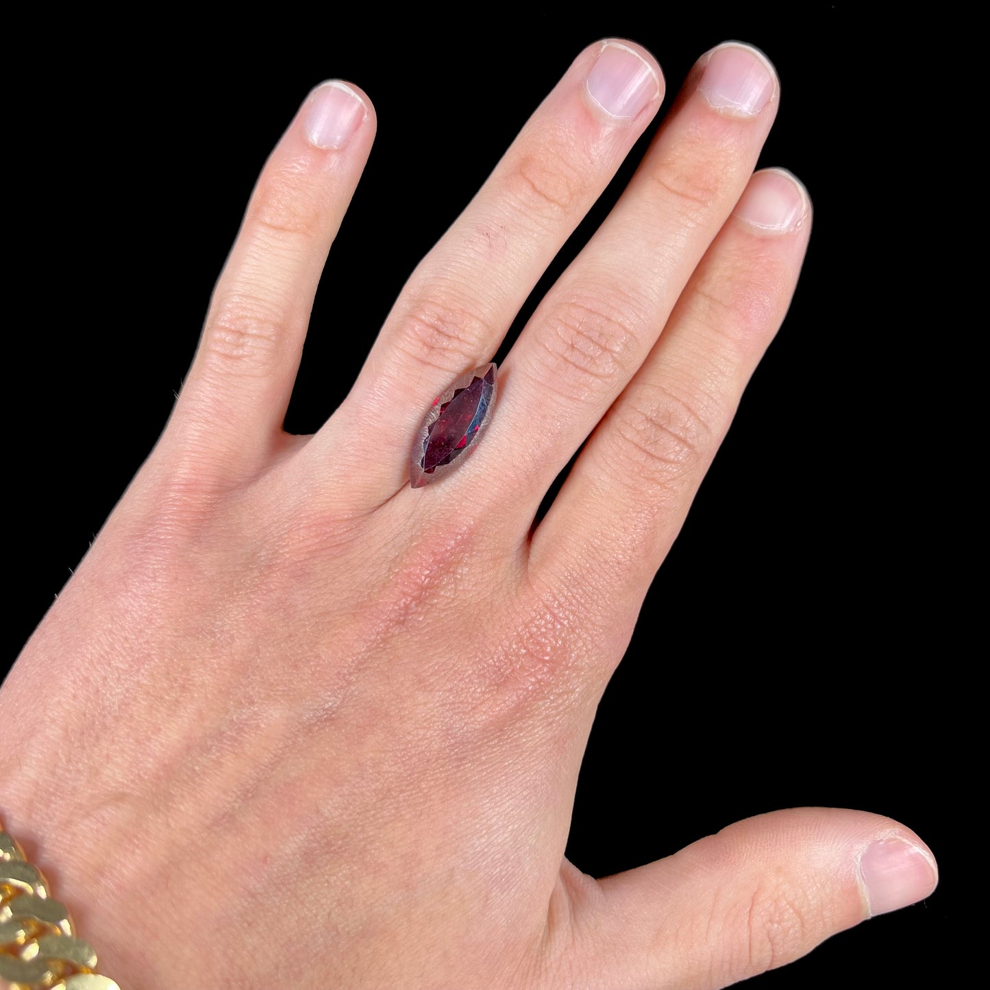 A loose, marquise cut cuprite gemstone.  The stone is a deep, crimson red color.